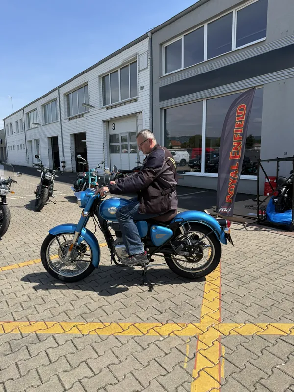 Fahrer auf einer blauen Royal Enfield vor der GARAGE