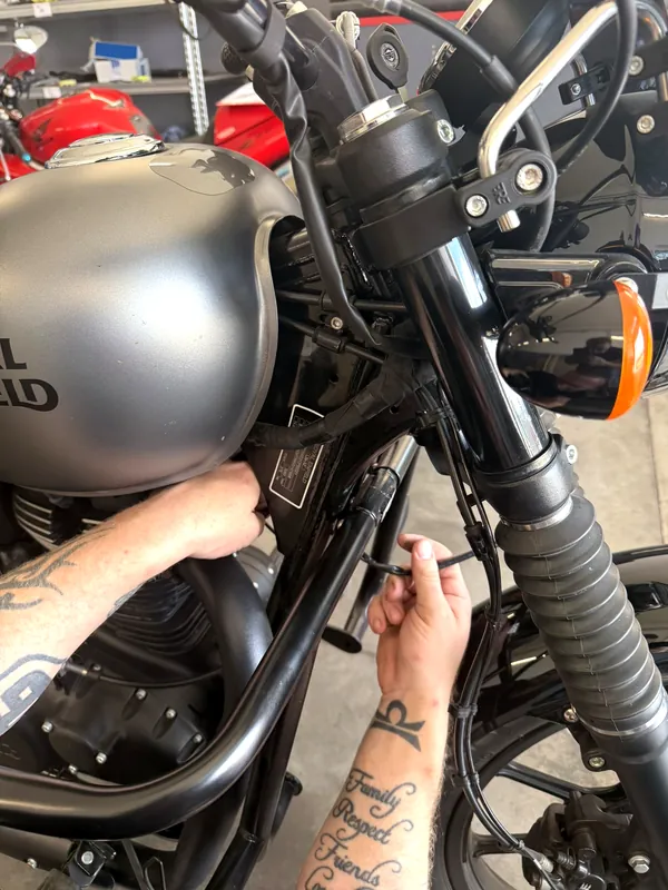 Ein GARAGE-Mechaniker montiert Zubehör an einem Royal Enfield Motorrad