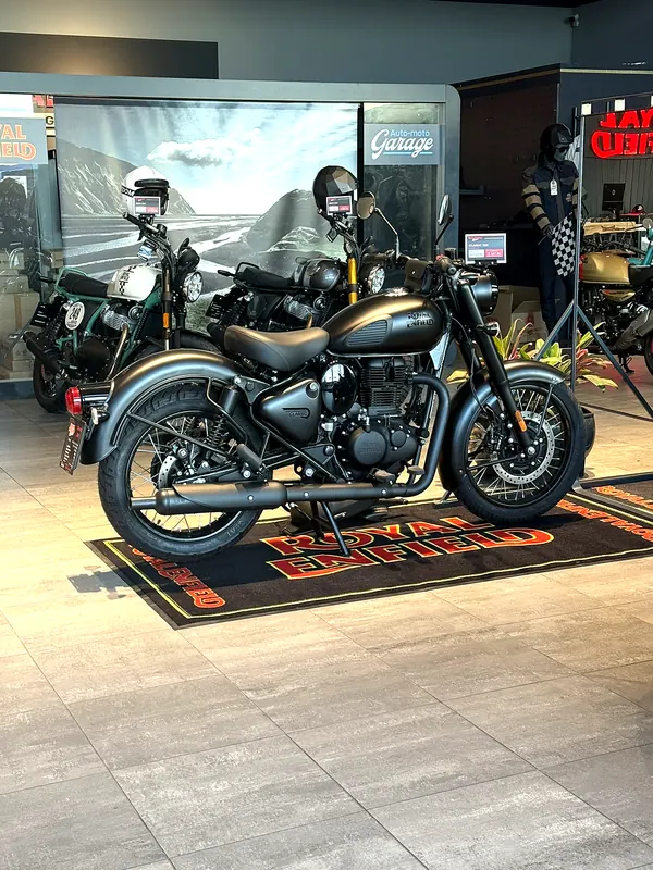 A motorcycle on a Royal Enfield carpet by the GARAGE wall
