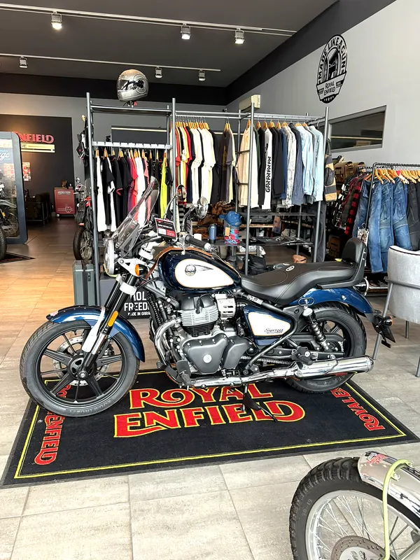 A motorcycle on a Royal Enfield carpet in front of clothing