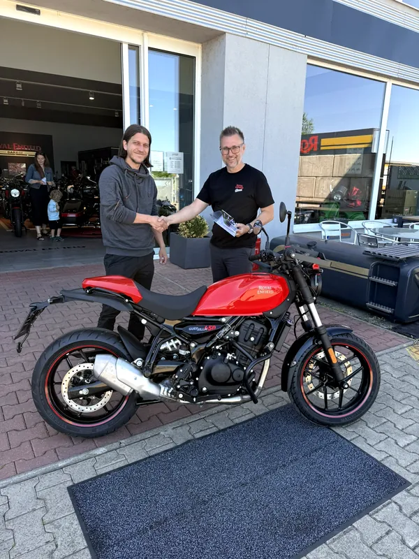 Übergabe eines Royal Enfield Motorrads an einen Kunden vor der GARAGE
