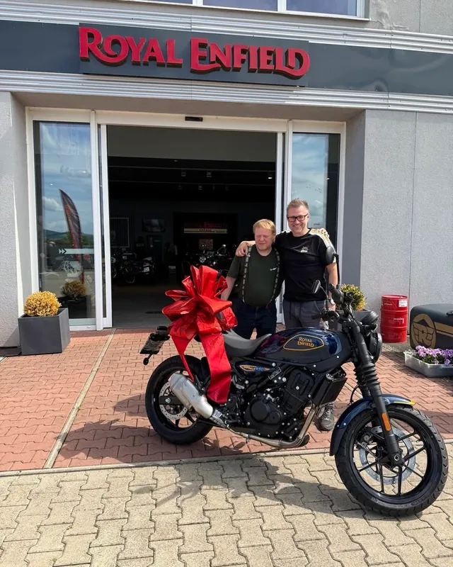 Übergabe eines neuen Royal Enfield Motorrads mit Schleife vor der GARAGE